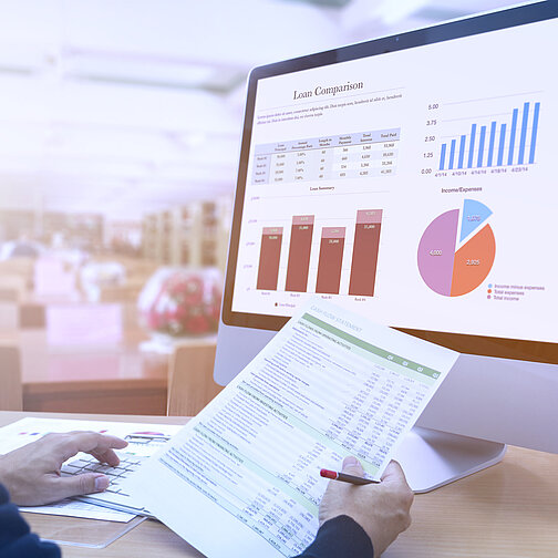 Person analysiert Daten am Computer und auf Papier